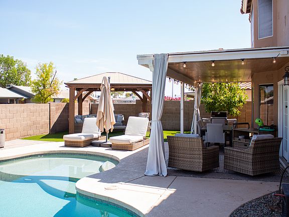 The backyard has an unheated pool, a Weber grill, a dining area for 6 and a lounge area that includes a fan. The yard is turf.