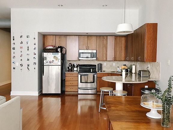 Pendant light, and recess lighting in kitchen. Countertop workspace with attached high bar seating.