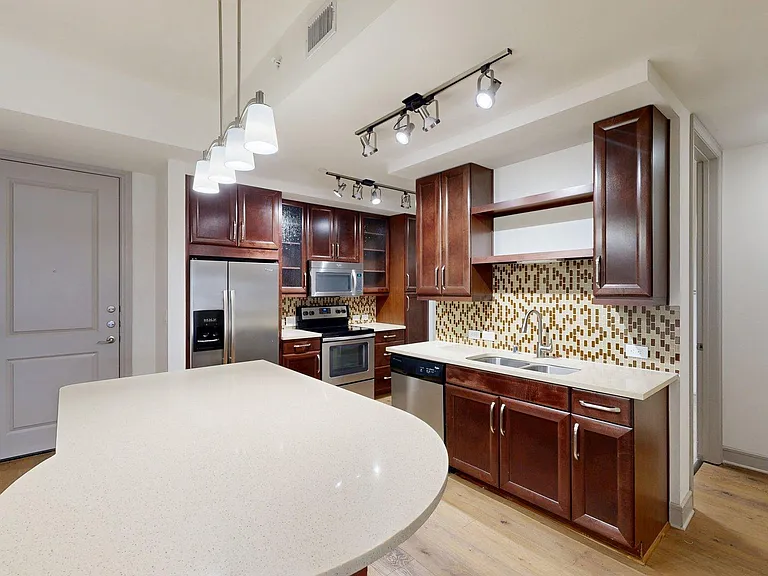 Apartment Kitchen with Quartz counter tops and Wood Style Flooring.