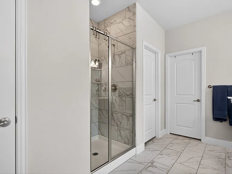 Shower enclosure with clear glass door and brushed nickel hardware, featuring white and gray veined tile surround