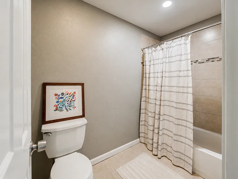 Shared Jack & Jill bathroom connecting Suites 1 & 2. Features a double-sink vanity with ample counter and cabinet space, bright lighting, and a full bathtub with shower. Each bedroom has its own private entrance for added convenience.