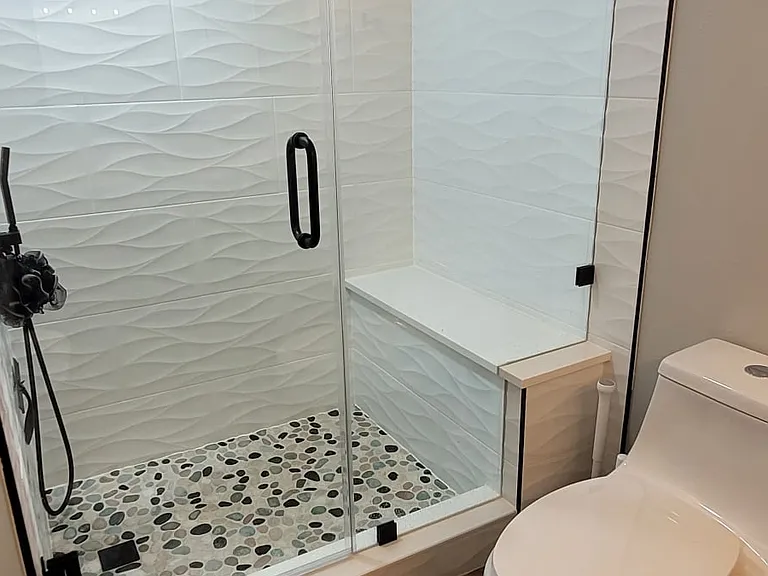 Brand new walk-in shower with rainfall shower head, wave tile and pebble floor.