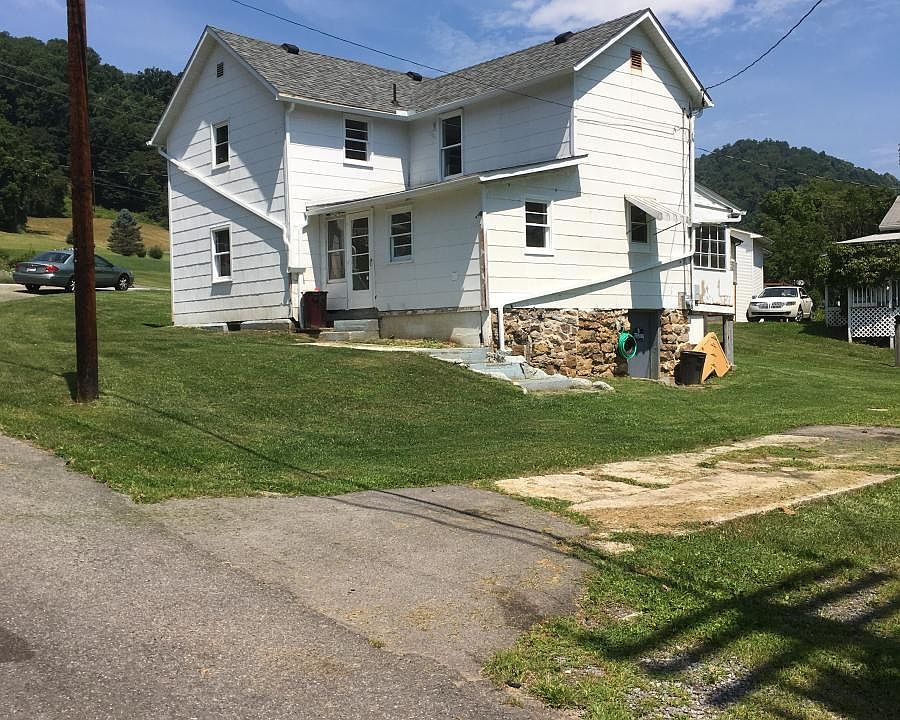 Back of house with stone foundation and private driveway.