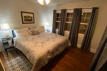 Back Bedroom with King bed, TV, dresser, closet, lots of windows & blackout curtains