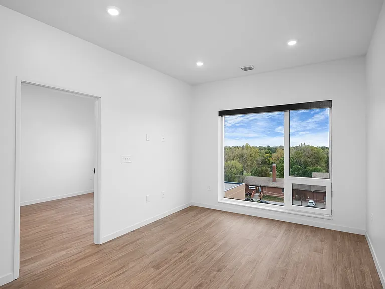 Bright and airy room with wooden flooring and a large window showcasing scenic treetop views, perfect for a cozy living space. Bright and airy room with wooden flooring and a large window showcasing scenic treetop views, perfect for a cozy living space.