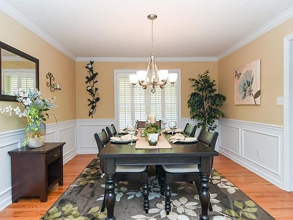 the formal dining room featuring updated chandelier, hardwood floors,  board & batton wainscoting, crown molding and plantation 