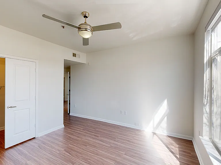 Spacious apartment bedroom with wood-style flooring.