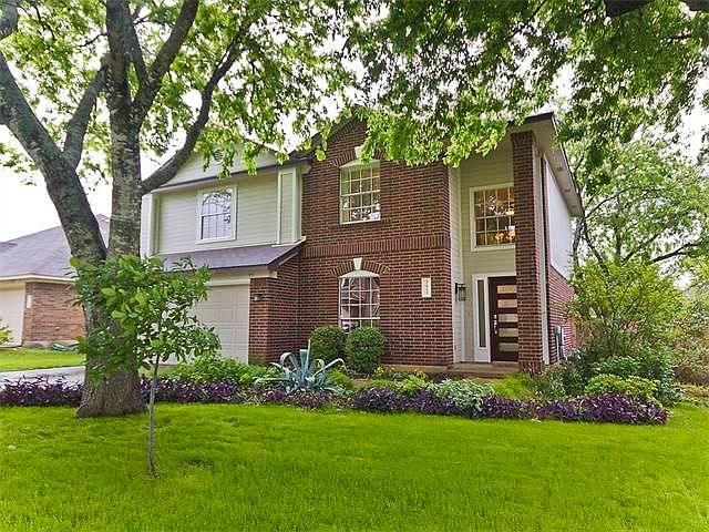 Beautiful brick home in Village at Wester Oak with lush yard and large trees.