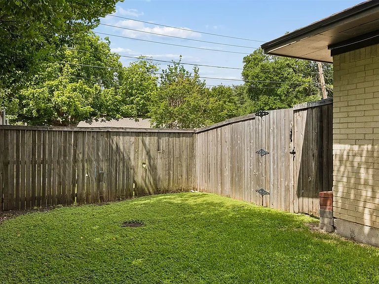 Private backyard area featuring a manicured lawn and wood fencing