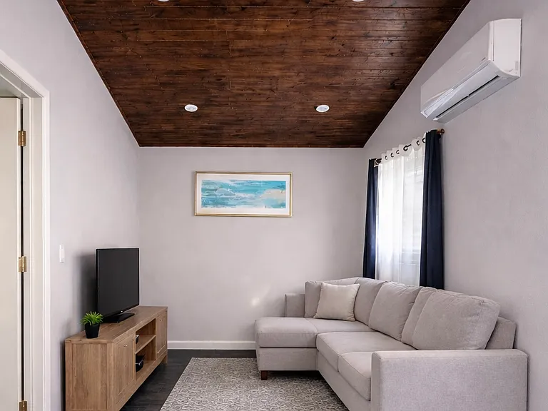 Livingroom, vaulted ceiling, tile floor and AC. Small living room best suited for a compact L-shaped sectional or a medium size couch. staged for marketing. Furniture not included.