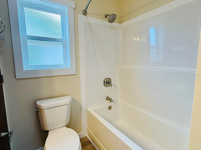 Large full-size bathroom with full size tub and shower, hot water heater, toilet, linen closet and clothes washing station