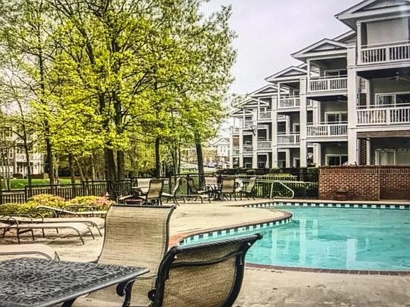 2nd floor condo balcony view of community pool with table and chairs. Surrounded by the beautiful waterfront and wildlife.