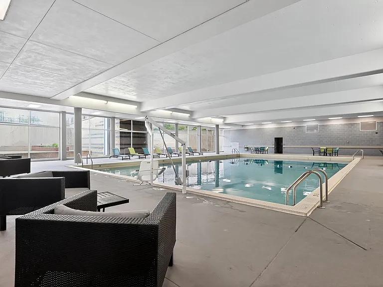 Modern indoor pool area with sleek lounge seating and expansive glass windows, perfect for relaxation and recreation.