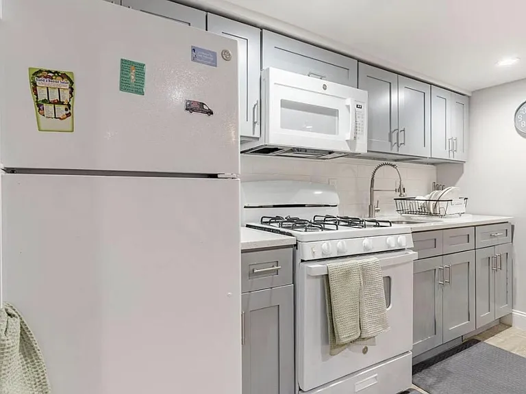 Efficient galley kitchen with ample gray cabinetry, full-size appliances, and generous counter space with a dish rack and dee