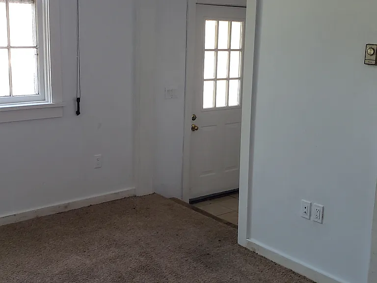 Living room with step down to front entrance. Brand new Carpet. As in 10x11 Bedroom (not pictured).