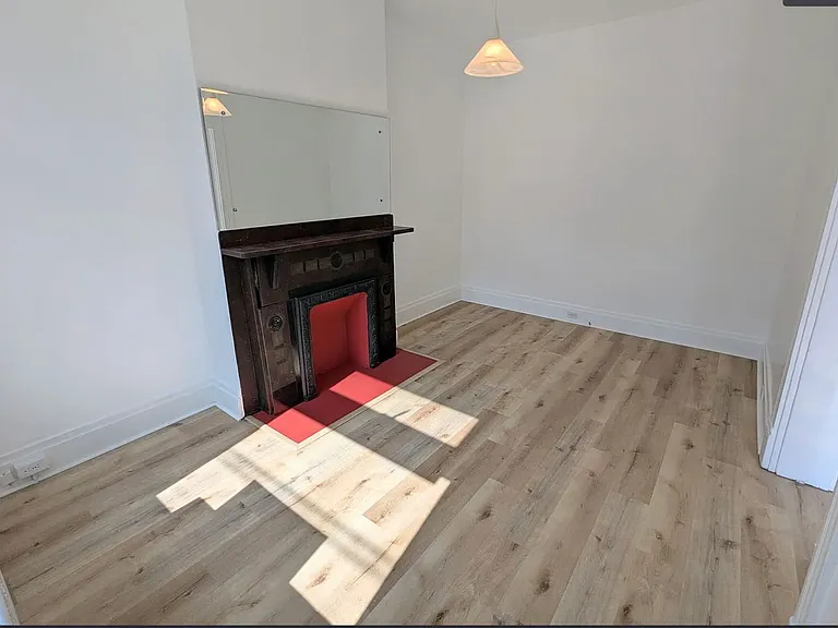 1st Floor Front Room_ Living Room, with a lot of natural light flowing in, another antique fireplace w/ a bright red hearth (& mirror above it) and brand new Luxury Vinyl Plank flooring (wood-like and warm)