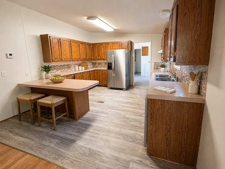 Spacious kitchen featuring abundant cabinet storage, stainless-steel dishwasher, refrigerator with built-in ice maker, and a convenient breakfast bar with room for seating.