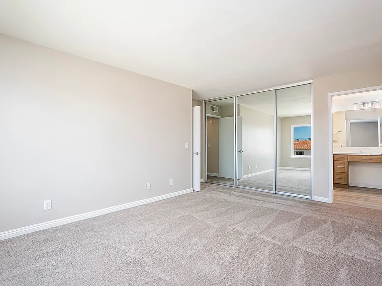 Primary bedroom with mirrored sliding closet doors and privacy door to the primary bathroom.