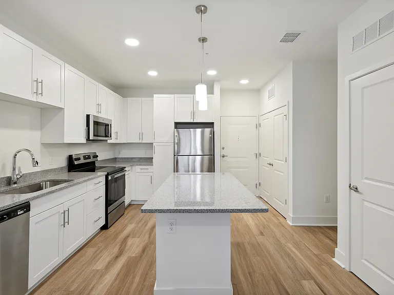Bright and modern kitchen with sleek stainless steel appliances, elegant granite countertops, and stylish white cabinetry exuding contemporary charm.