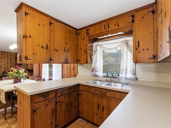 Kitchen with a peninsula, wood finish cabinets, light countertops, and plenty of natural light