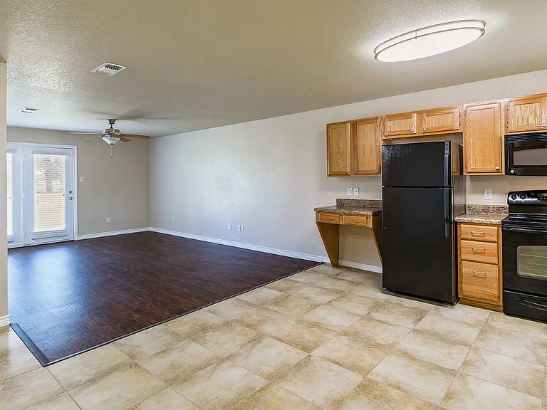 View of the living area from the kitchen in a Phase 2 apartment home. The glass doors lead to the back porch.