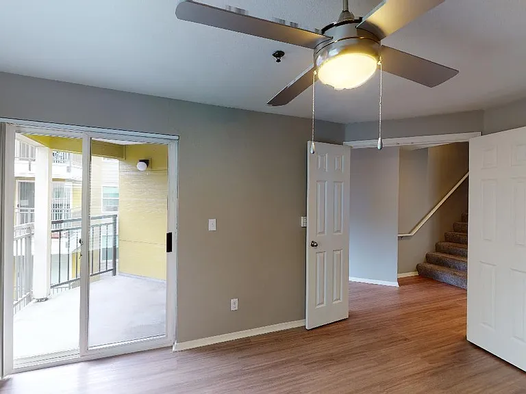 Apartment living room with wood-style flooring and balcony in select homes.