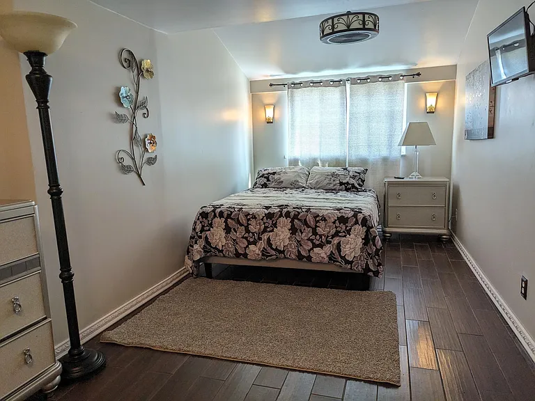 Master bedroom. TV swings out. Ceiling light fixture has fan. Windows face backyard patio.