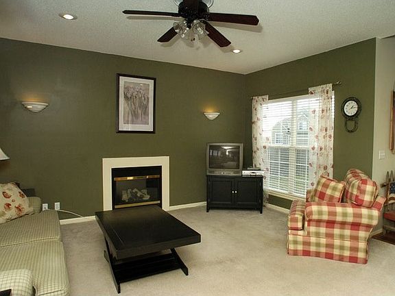 Great room with window coverings, fireplace, and ceiling fan
