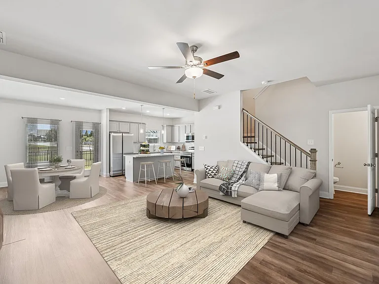 View of the living room area featuring an open staircase and refined dining space.