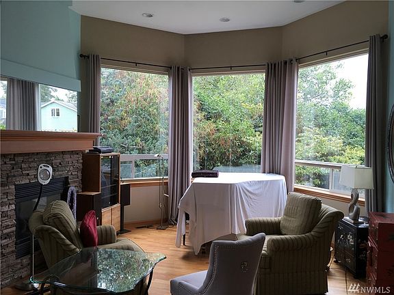Formal living room with real wood floors, gas fireplace, and large windows all with motorized shades.