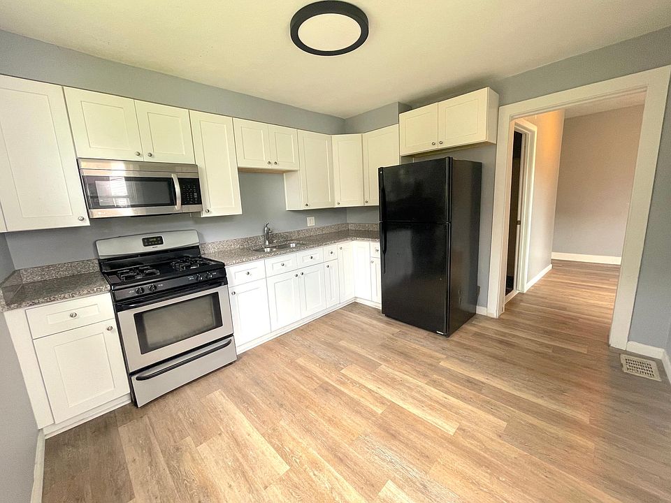 white shaker modern kitchen with granite countertop, stainless steel appliances.