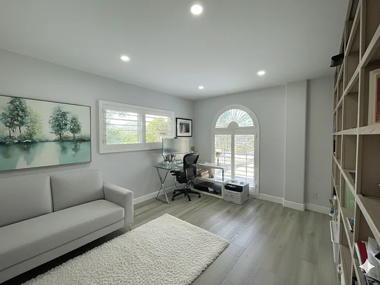 A versatile bedroom or home office features a large built-in bookshelf, offering the perfect setup for working from home or relaxing with a good book.
