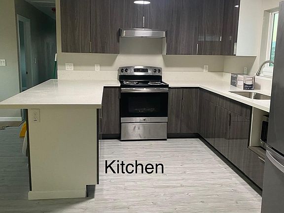 Kitchen with stainless steel appliances, quartz countertops, and bright LED lights