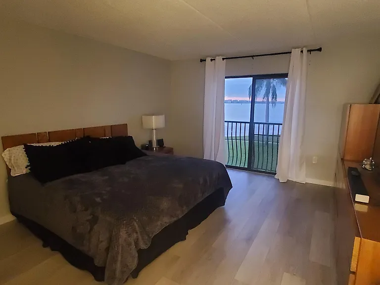 Primary bedroom with sliding doors and view of private beach and sand key bridge