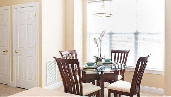 View from breakfast bar towards dining area of great room also showing storage and utility closet doors in hallway to bedroom