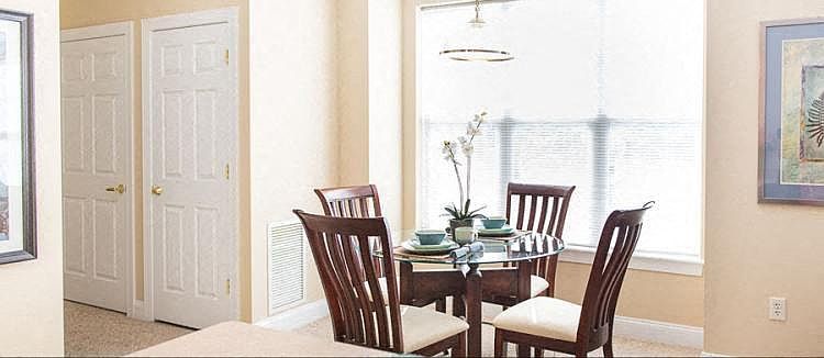 View from breakfast bar towards dining area of great room also showing storage and utility closet doors in hallway to bedroom