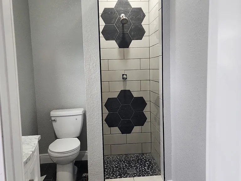 Bathroom with tile shower and flooring. Quartz countertop