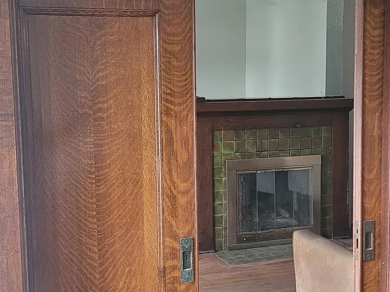 4th bedroom on main level with tiger wood double doors, and fireplace, TV, couch in the room