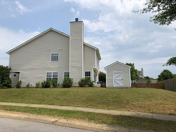 Side yard faces Red Oak Drive, secure storage shed with lawn mower provided.