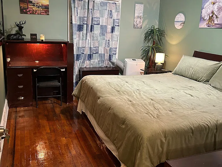 Furnished bedroom with hardwood floors, a dedicated desk/workstation, bedside table, and ceiling fan lighting.