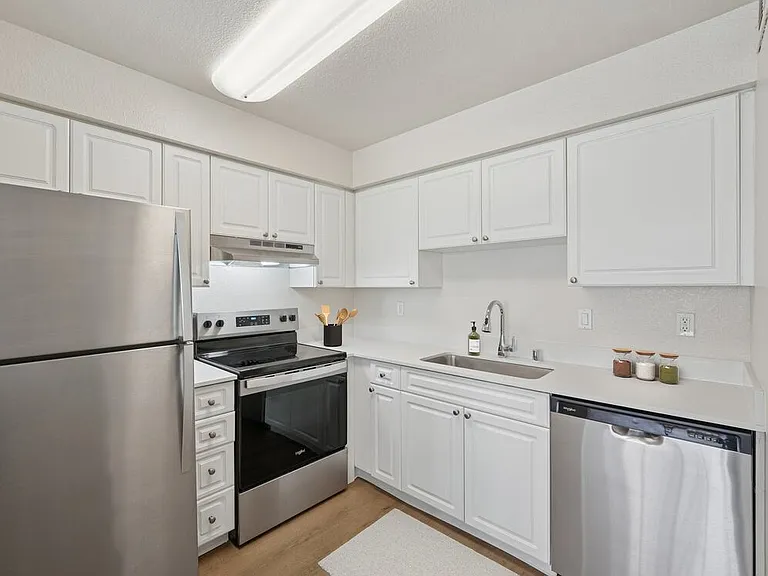 Renovated Package I kitchen with stainless steel appliances, white cabinetry, quartz countertops, and hard surface flooring