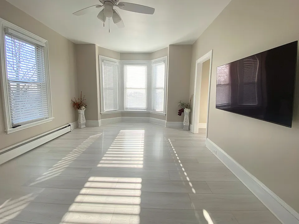 An open, sun-filled living area with brand-new flooring and a seamless transition toward a dedicated office/den, creating a flexible and thoughtfully designed layout.