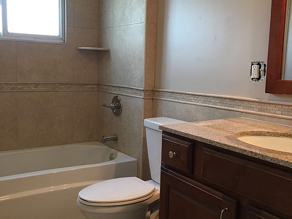 Travertine tiles design, deep tub, big wood cabinet with gra
