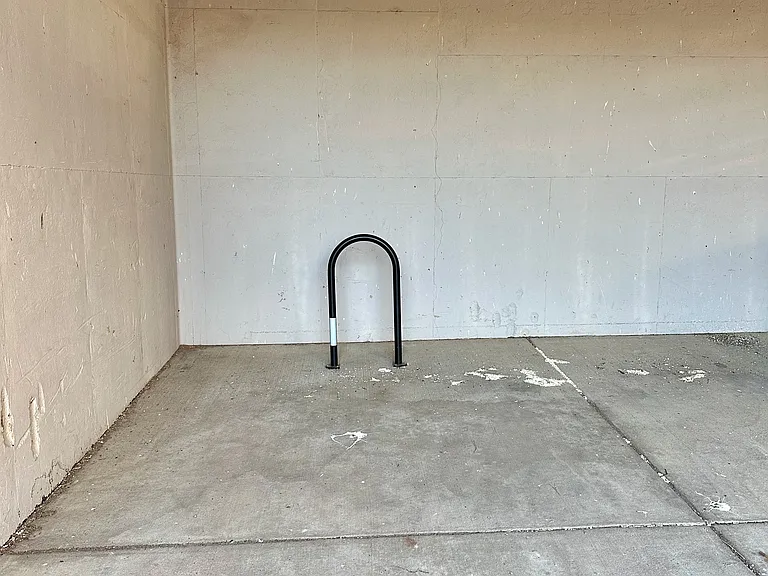 Reserved, extra-high carport with concrete-embedded bike rack for secure gear storage.