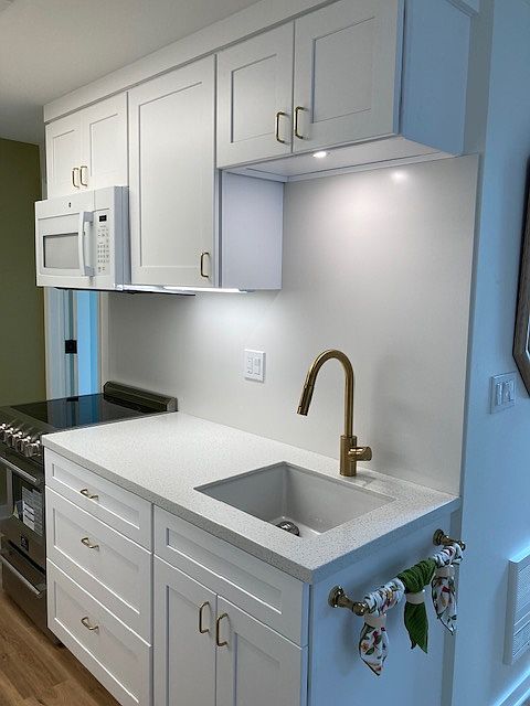 Kitchen range, microwave, sink with garbage disposal and under-cabinet lighting throughout