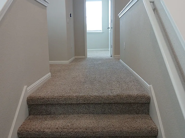 Stairs leading to small office space at the left, two bedrooms and a bathroom