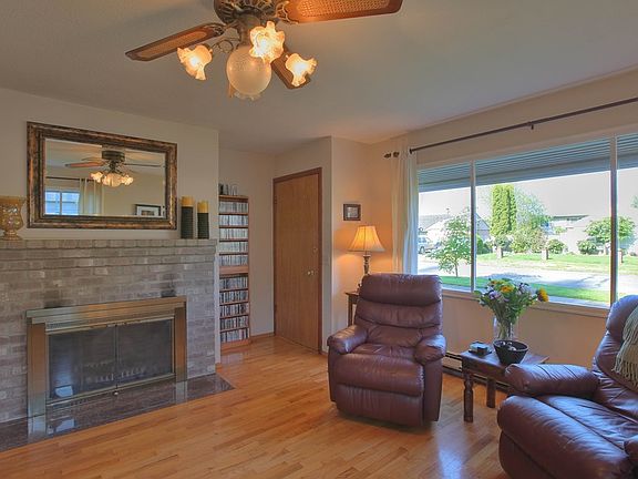 Living Room with hardwood floors, fireplace with mantle, large picture windows.