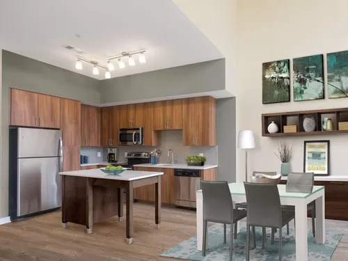 Upgraded dining area and kitchen with walnut cabinetry, white quartz countertops, light grey tile backsplash, stainless steel appliances, and hard surface flooring - Avalon Mosaic