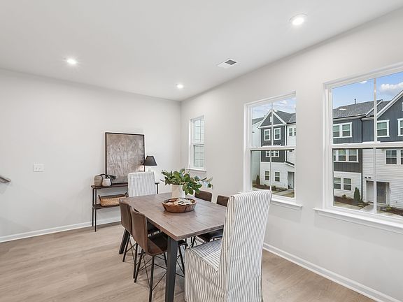 A modern, open-concept dining area with a wooden table and chairs, surrounded by large windows overl