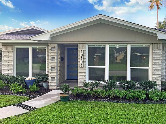 Another close up view of the entry showing replaced double glazed vinyl windows, precise landscaping, and glass block accented column